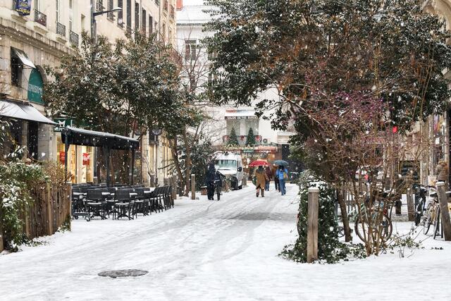 Photo de passants qui marchent dans les rues enneigées du centre ville de Grenoble