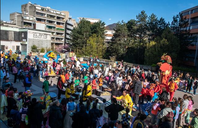 Photo du défilé des marionettes géantes suivies par le cortège des enfants déguisés et de la battucada.