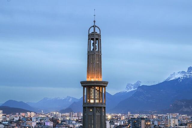La nuit, l'éclairage intérieur de la tour Perret est allumé. Le Vercors est visible.