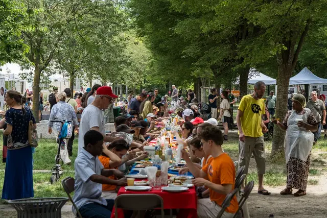 Photo d'une grande tablée rassemblant des citoyennes et des citoyens de tous âges autour d'un repas partagé.