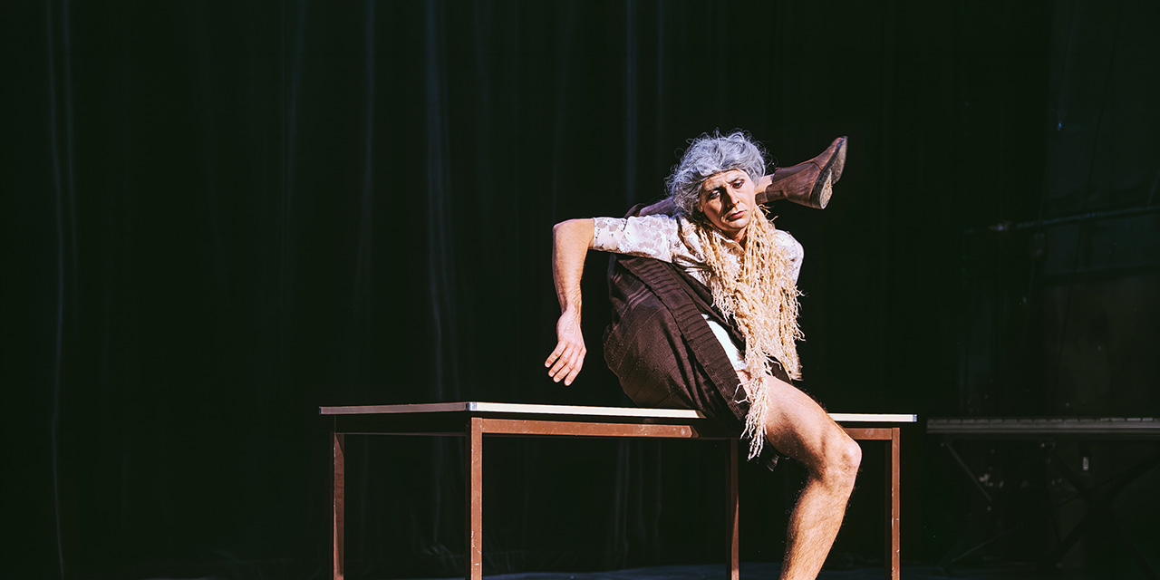 Un circassien se contorsionne sur une table.