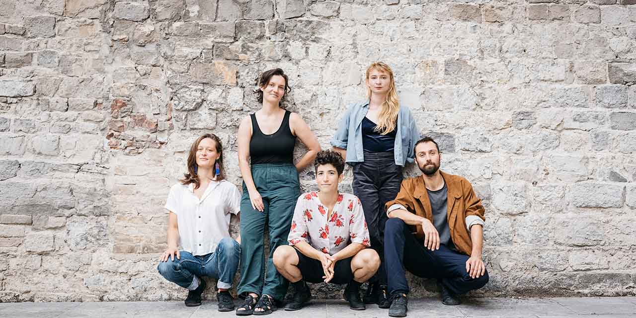 Le collectif pose devant un mur de pierres