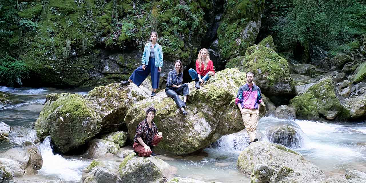 Le collectif pose sur des pierres au milieu du lit d'une rivière