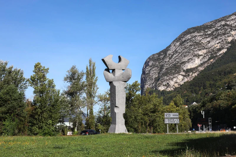 La colonne olympique trône sur une bande de pelouse, le Néron comme toile de fond.